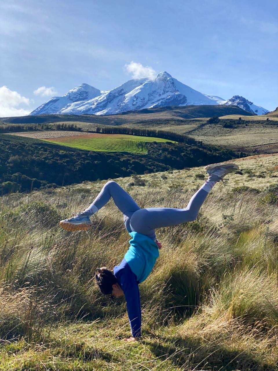 Dana haciendo equilibrio de manos en un paisaje de montaña
